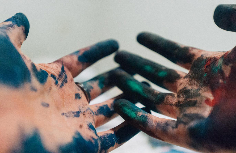 Photo of a pair of artist's hands covered in paint