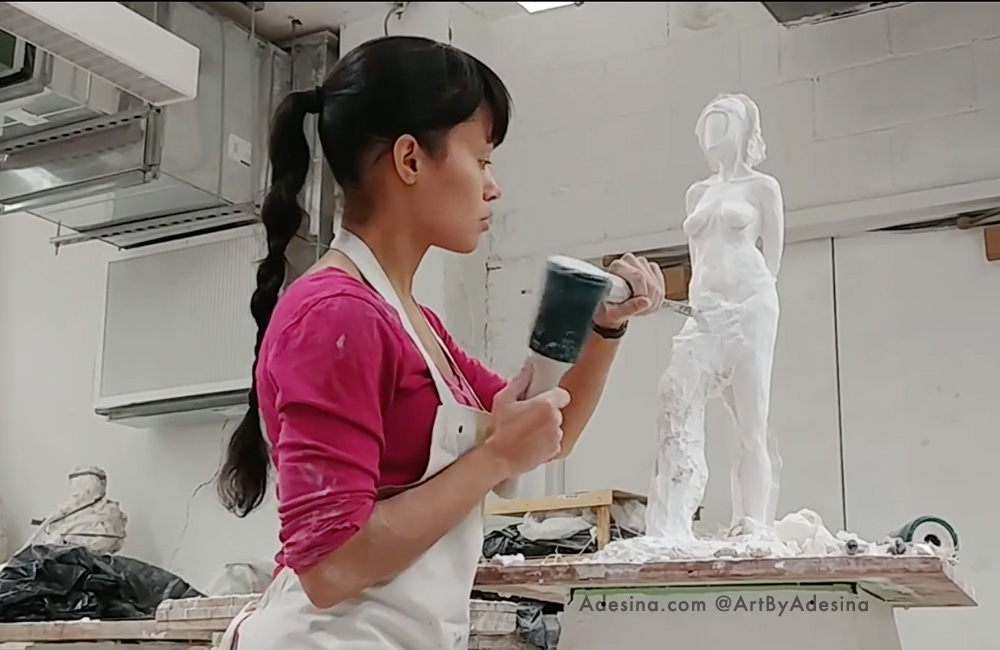 Photo of artist Adesina Sanchez in the art studio, working on a sculpture
