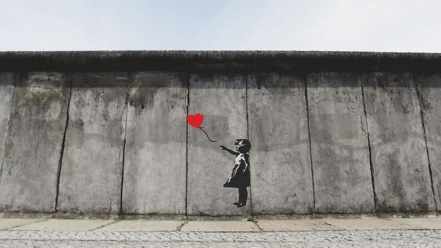 Photo of a mural on a gray wall, with a child and a red balloon