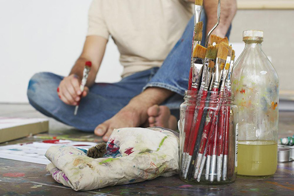 Photos of an artist sitting barefoot with brushes